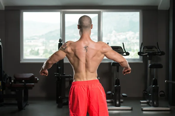 Homem muscular flexionando músculos no ginásio — Fotografia de Stock