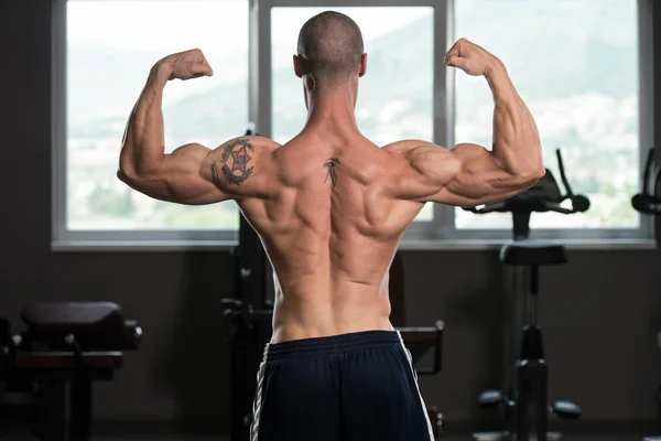 Homem muscular flexionando músculos no ginásio — Fotografia de Stock