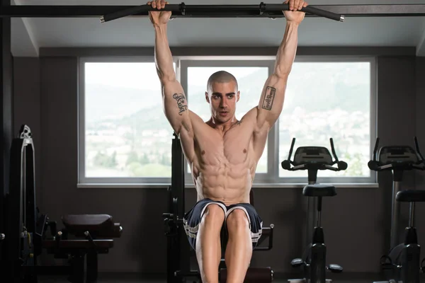 Joven hombre realizando colgante pierna plantea ejercicio — Foto de Stock