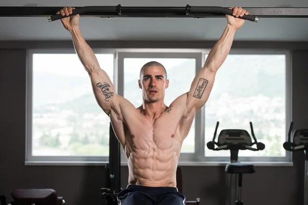 Jovem realizando pendurado perna levanta exercício — Fotografia de Stock