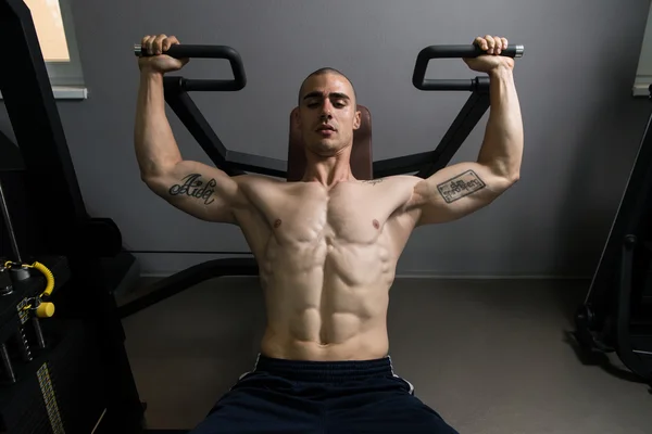 Мускулистый человек делает тяжелые упражнения веса для плеч — стоковое фото