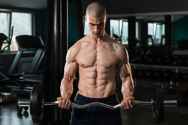 Homem muscular exercitando bíceps com barra — Fotografia de Stock