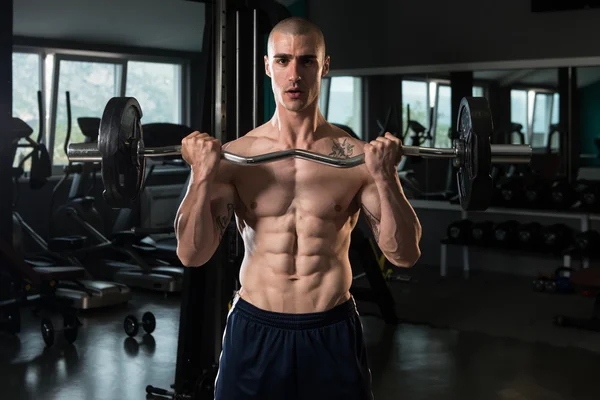 Homem muscular exercitando bíceps com barra — Fotografia de Stock