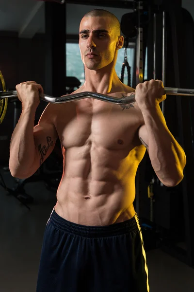 Muskulöser Mann trainiert Bizeps mit Langhantel — Stockfoto