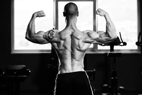 Musculoso hombre flexionando los músculos en el gimnasio —  Fotos de Stock