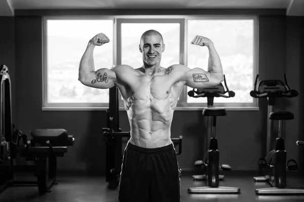 Musculoso hombre flexionando los músculos en el gimnasio — Foto de Stock