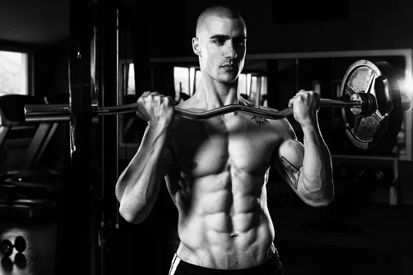 Man in de sportschool uitoefening biceps met barbell — Stockfoto