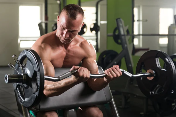 Man in de sportschool uitoefening biceps met barbell — Stockfoto