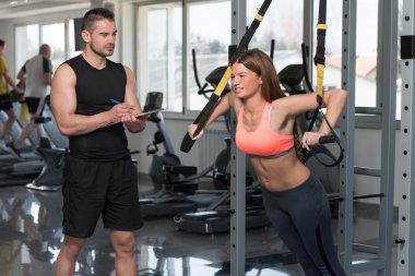 Eğitmen Trx Fitness kayışları üzerinde Pano kadınla