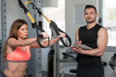 Eğitmen Trx Fitness kayışları üzerinde Pano kadınla