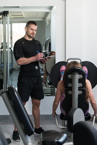 Kişisel antrenör kadın bacaklar egzersiz sırasında notlar alır — Stok fotoğraf