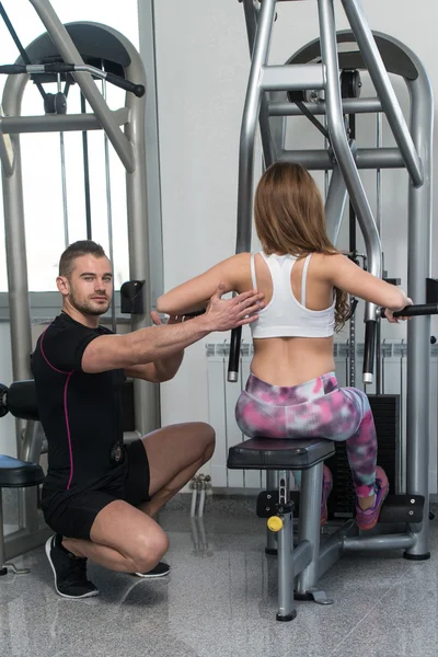 Mujer tren de vuelta en la máquina con entrenador personal — Foto de Stock