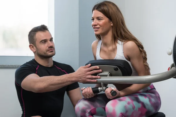 Entrenador de gimnasio ayudando a la mujer en el ejercicio de espalda —  Fotos de Stock