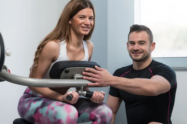 Entraîneur personnel aidant client dans la salle de gym — Photo