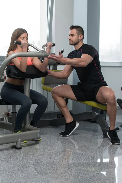 Entrenador de gimnasio ayudando a la mujer en el ejercicio de bíceps —  Fotos de Stock