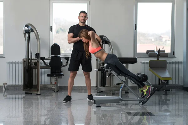 Entrenador de gimnasio ayudando a la mujer en el ejercicio de espalda —  Fotos de Stock