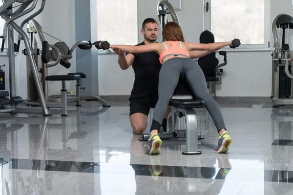 Entrenador de gimnasio ayudando a la mujer en el ejercicio de espalda —  Fotos de Stock