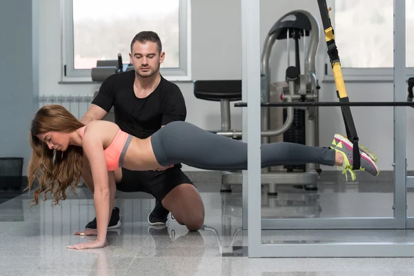 Entrenador de gimnasio ayudando a la mujer en correas de fitness Trx — Foto de Stock