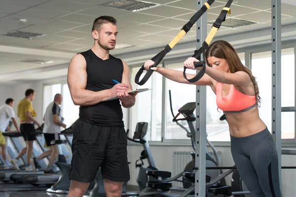 Entrenador con la mujer del portapapeles en correas de fitness Trx —  Fotos de Stock