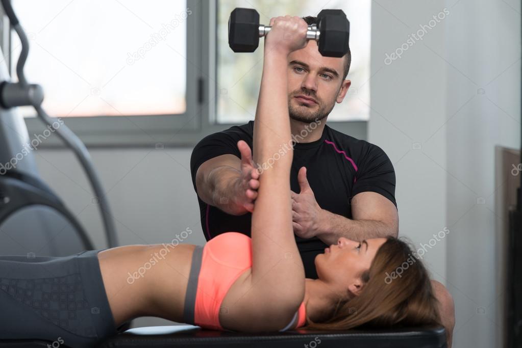 Gym Coach Helping Woman On Triceps Exercise