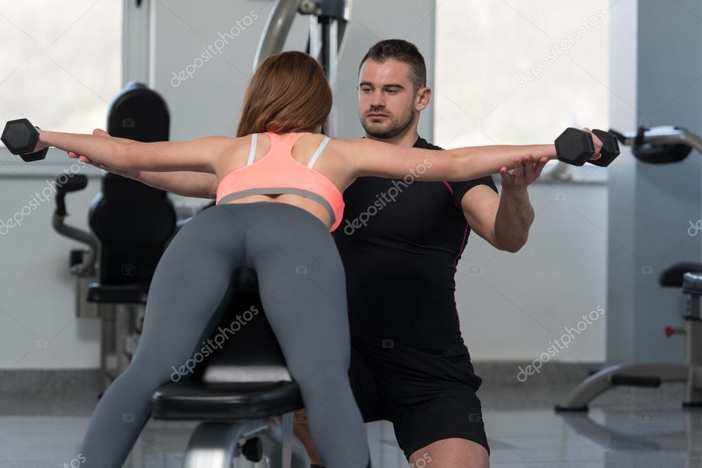 Personal Trainer Helping Woman On Back Exercise