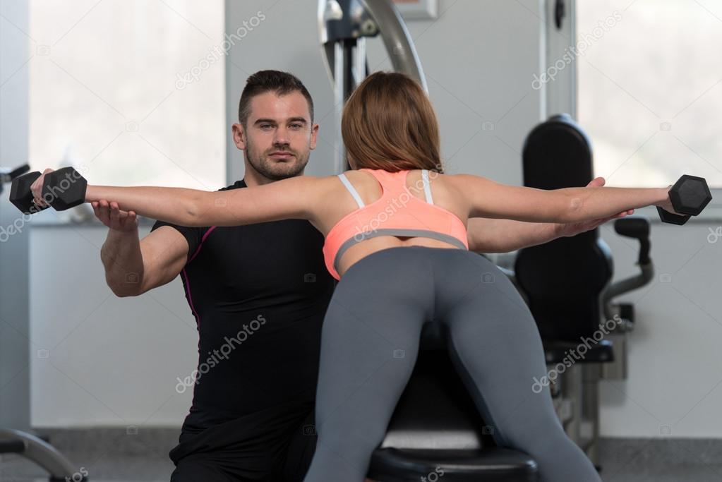 Gym Coach Helping Woman On Back Exercise