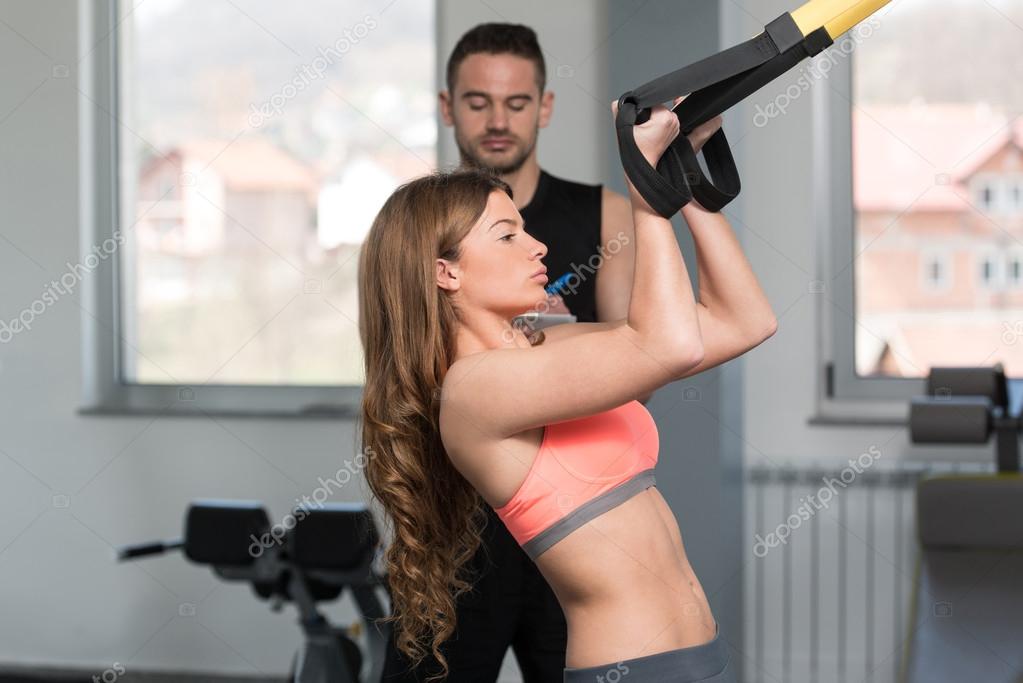 Personal Trainer Helping Woman On Trx Fitness Straps