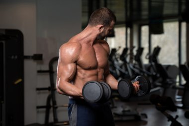 Man In The Gym Exercising Biceps With Dumbbells