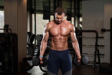 Man In The Gym Exercising Biceps With Dumbbells