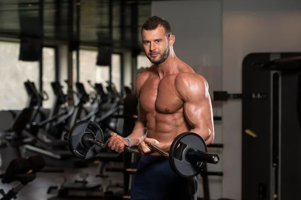Bodybuilder utför biceps lockar med en skivstång — Stockfoto