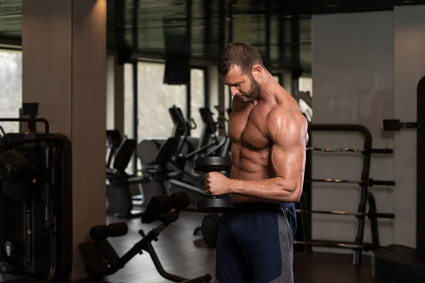 Muskularny mężczyzna ćwiczeń bicepsów z hantlami — Zdjęcie stockowe