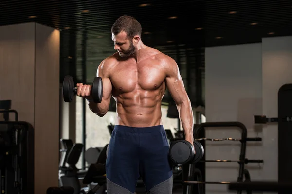 Muscular hombre ejercicio bíceps con sombrillas — Foto de Stock