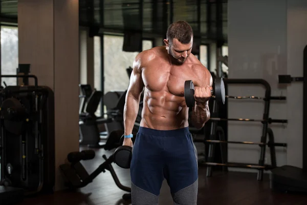 Mann im Fitnessstudio trainiert Bizeps mit Kurzhanteln — Stockfoto