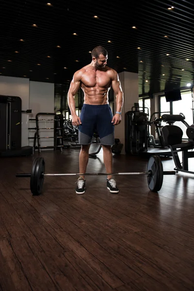 Hombre en el gimnasio haciendo ejercicio de nuevo con la barra —  Fotos de Stock