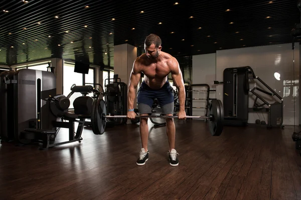 Homem muscular exercitando de volta com Barbell no ginásio — Fotografia de Stock