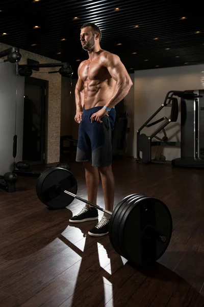 Muskulös Man tränar tillbaka med skivstång i Gym — Stockfoto