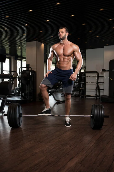 Homme musculaire s'exerçant en arrière avec Barbell dans le gymnase — Photo