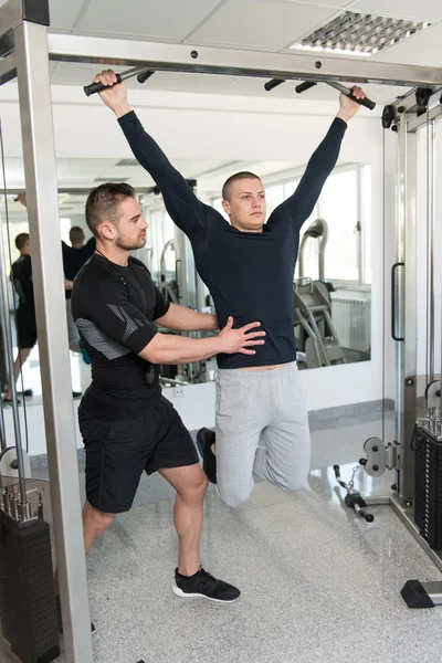Homem fazendo Pull-Ups Exercícios com treinador de ginásio — Fotografia de Stock