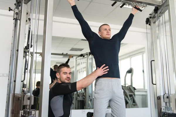 Homem fazendo Pull-Ups Exercícios com treinador de ginásio — Fotografia de Stock