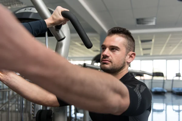 Trener siłowni pomaga młody człowiek na klatce piersiowej Ćwiczenia — Zdjęcie stockowe