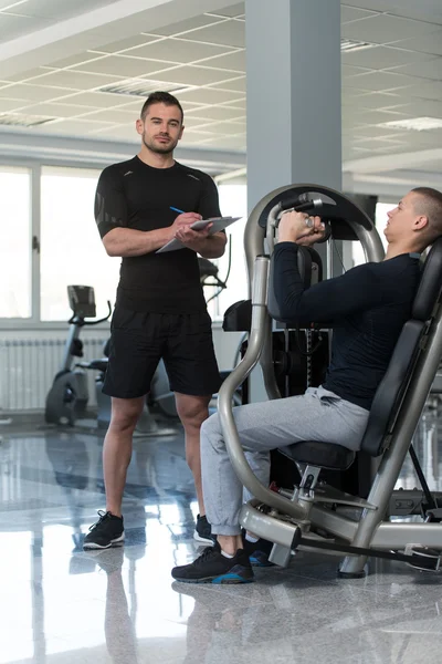 Personal Trainer Takes Notes While Man Exercising Chest — Stock Photo, Image