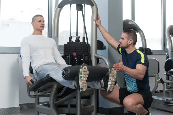 Palestra allenatore aiutare youg uomo su gambe — Foto Stock