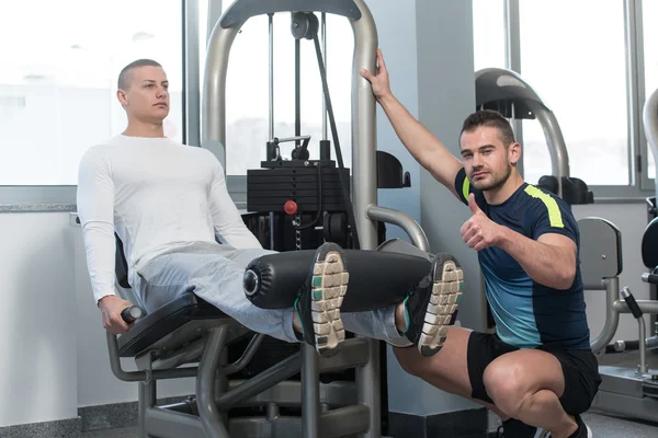 Man Train Legs On Machine With Personal Trainer — Stock Photo, Image