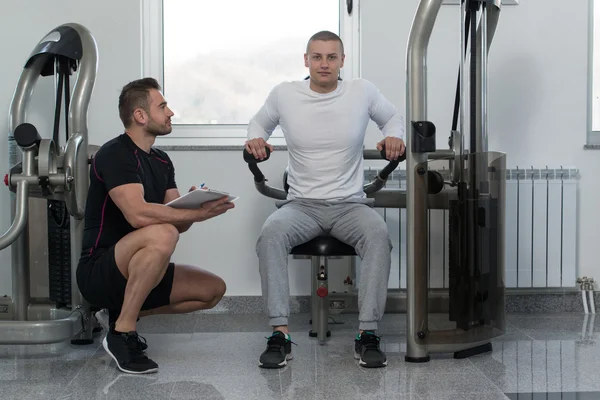 Trainer scrittura sugli appunti mentre l'uomo formazione Triceps — Foto Stock