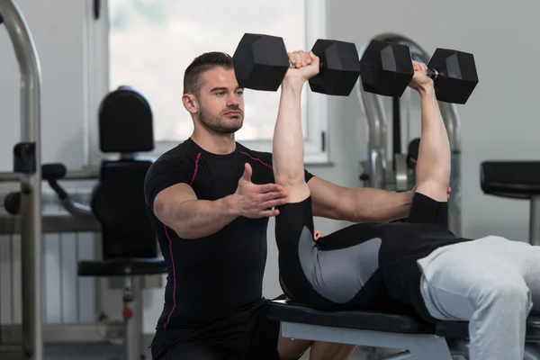 Entraîneur de gymnase aider l'homme sur l'exercice de poitrine — Photo