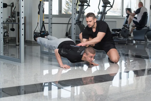 Personal Trainer helpt Man op Trx Fitness riemen — Stockfoto