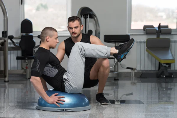 Entraîneur de gymnase aidant l'homme sur l'exercice Bosu Abs — Photo