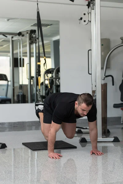 Aantrekkelijke jongeman opleiding met TRX ® Fitness riemen — Stockfoto