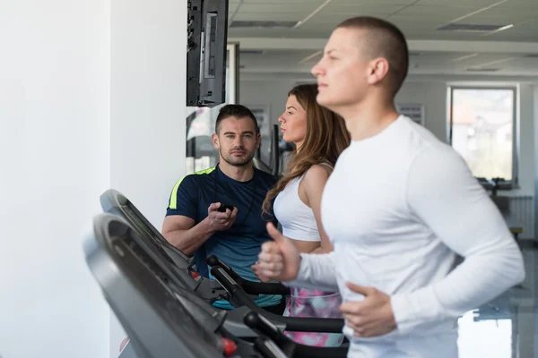 Groupe de personnes courant sur des tapis roulants dans la salle de gym — Photo