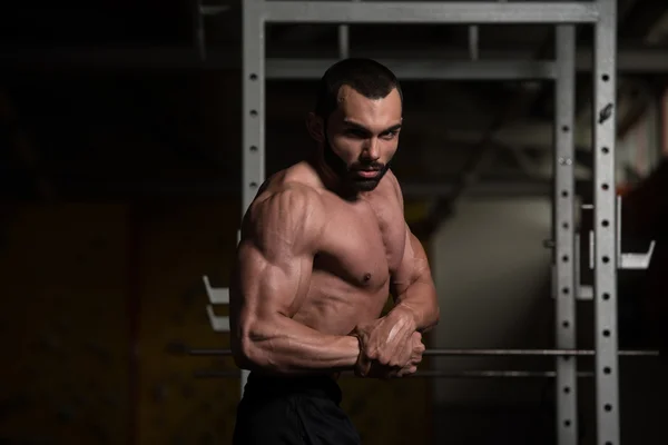 Uomo muscolare che flette i muscoli in palestra — Foto Stock